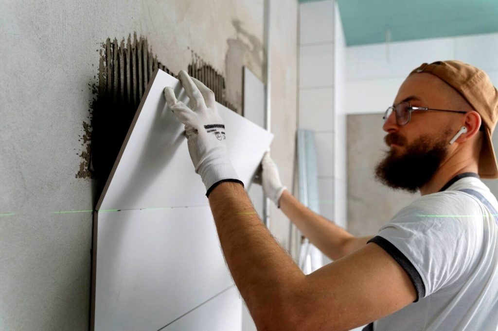 Carreleur travaillant sur la pose de carrelage mural