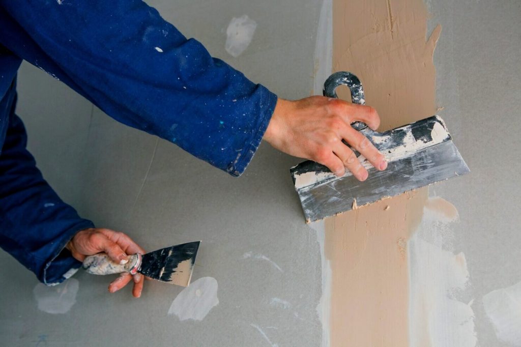 Homme travaille le mur avant de poser un carrelage