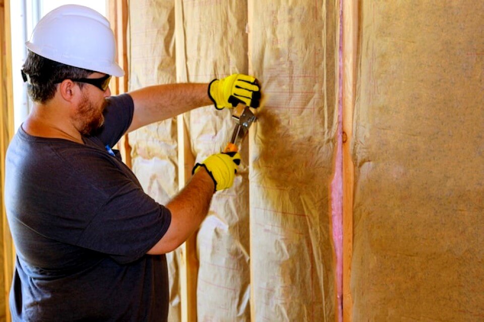 Travailleur installant une couche d'isolation thermique sous le mur