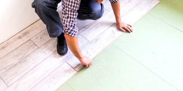 Un travailleur posant un parquet au sol