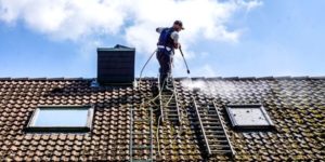 Professionnel qui démousse une toiture