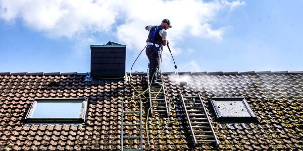 Professionnel qui démousse une toiture