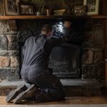 Ramoneur inspectant un conduit de cheminée avec une lampe torche